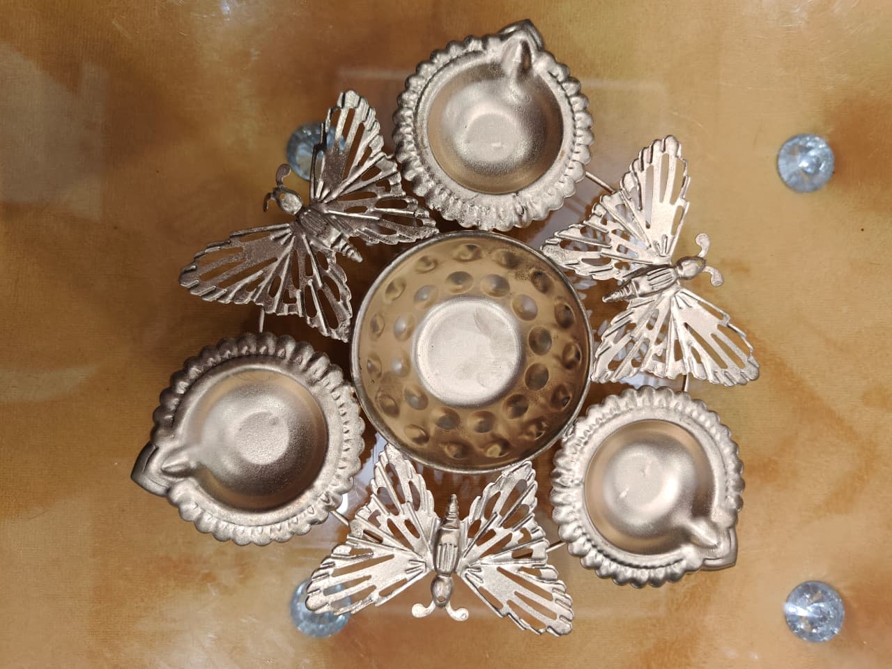 Silver butterfly diya set with 4 scalloped diyas and central bowl connected by butterfly figures, top view