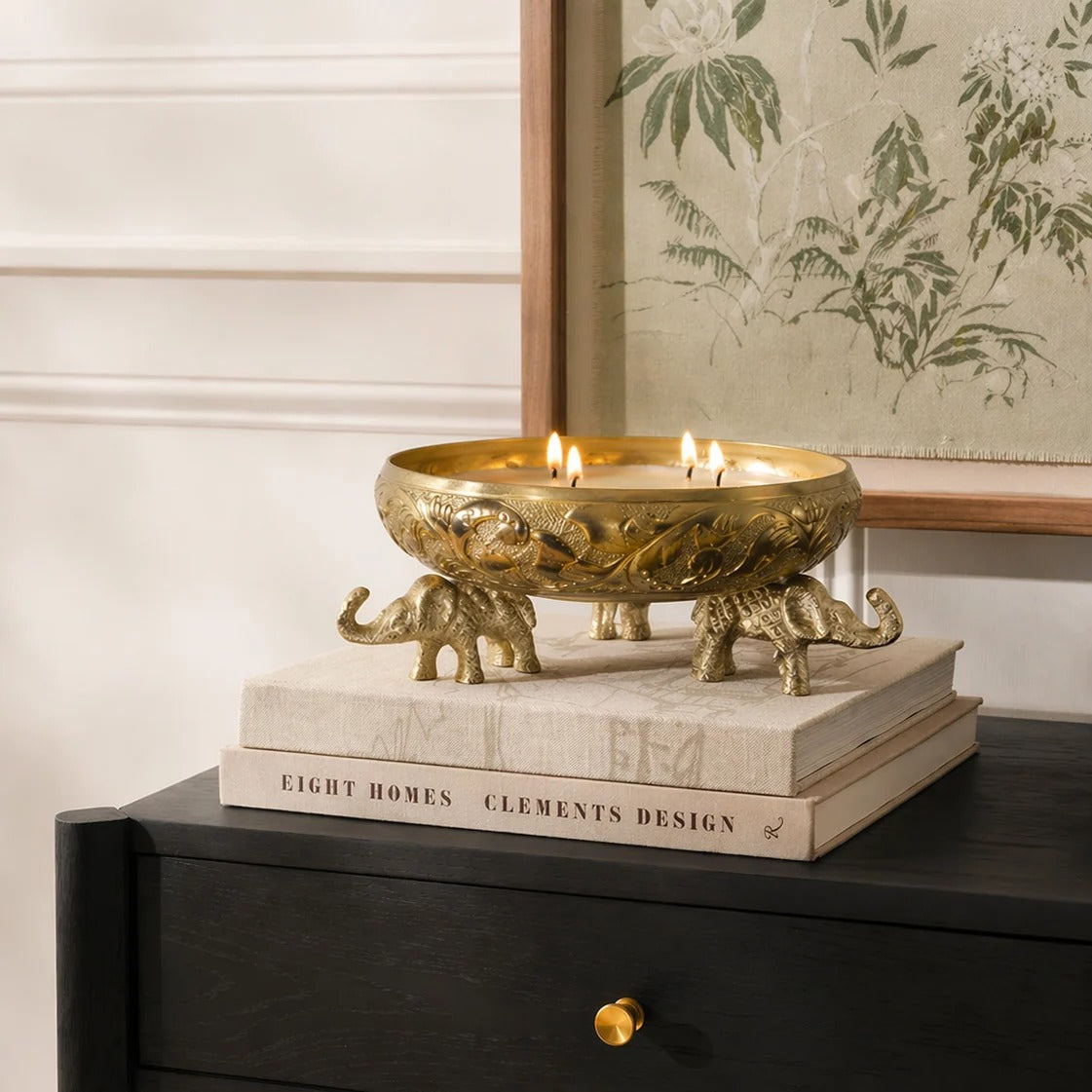Close-up detail of gold elephant urli showing intricate lotus floral embossing and elephant figurine leg