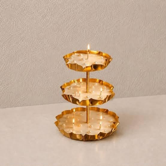 3-tier gold lotus petal tray stand on beige surface with white baby's breath flowers beside it
