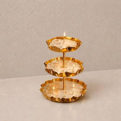 3-tier gold lotus petal tray stand on beige surface with white baby's breath flowers beside it