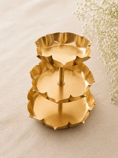 3-tier gold lotus petal tray stand with lit tealight candles on all three tiers on white surface
