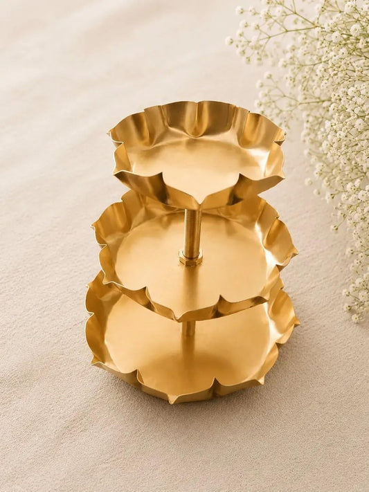 3-tier gold lotus petal tray stand with lit tealight candles on all three tiers on white surface