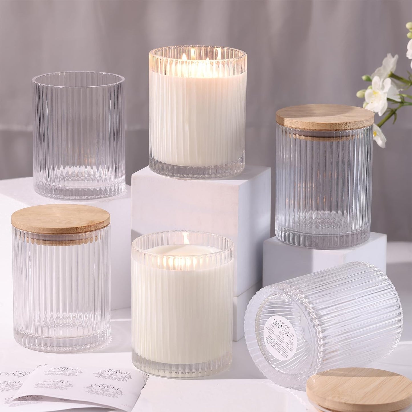 Set of 6 ribbed glass candle jars with bamboo lids arranged on white surface with lit candles