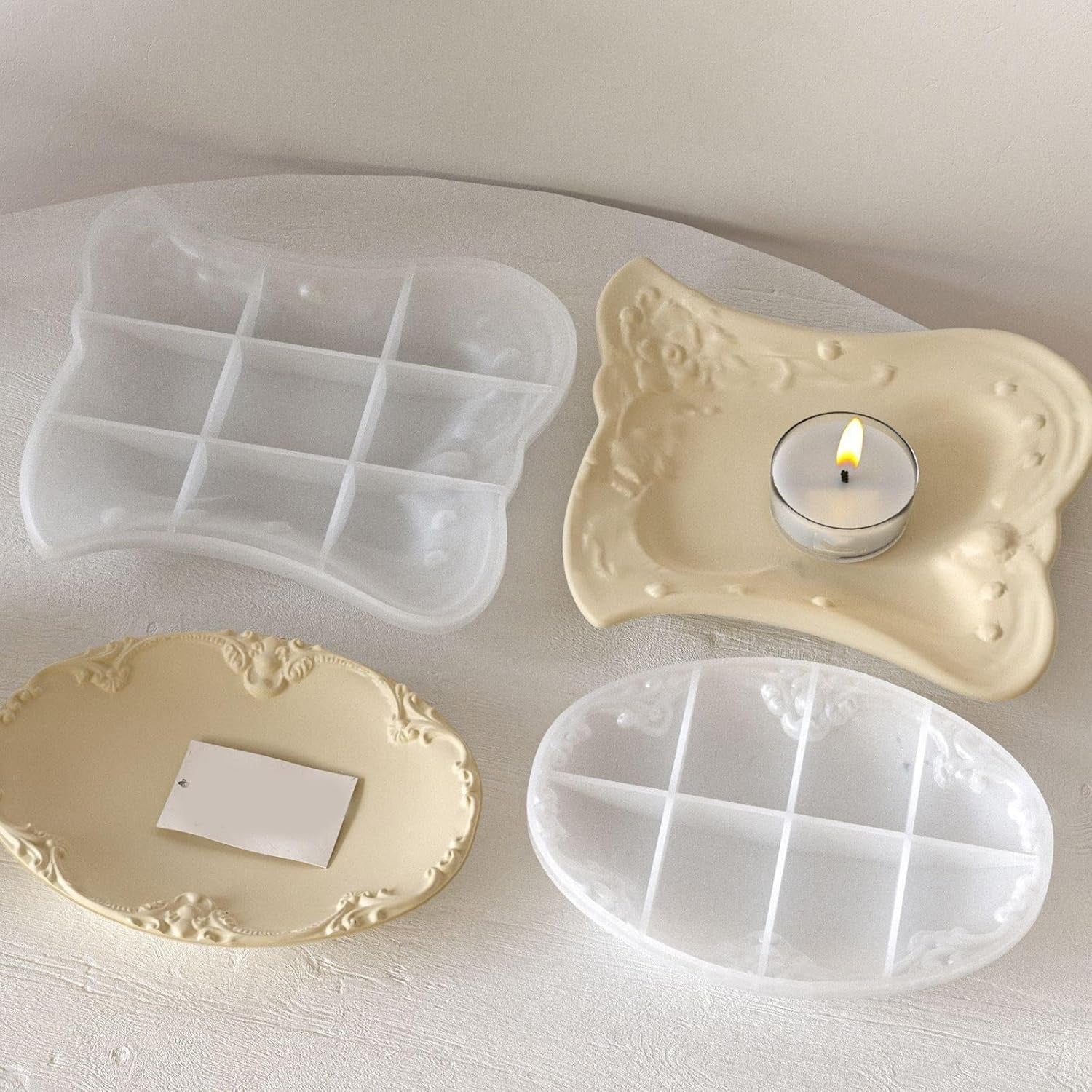 Finished cream vintage floral trays and moulds arranged on a round table with dried botanicals