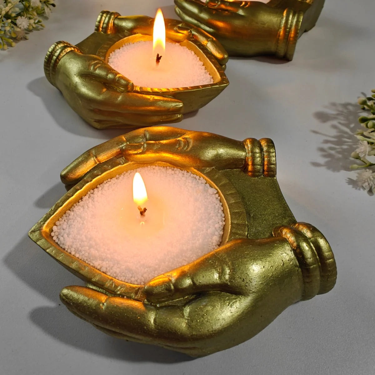 Arpan Diya Mould – gold finished candle holder with lit candle, front view
