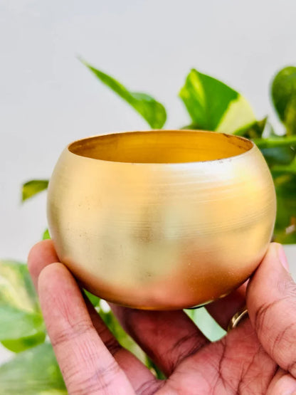 Matte gold ball candle tin on white surface