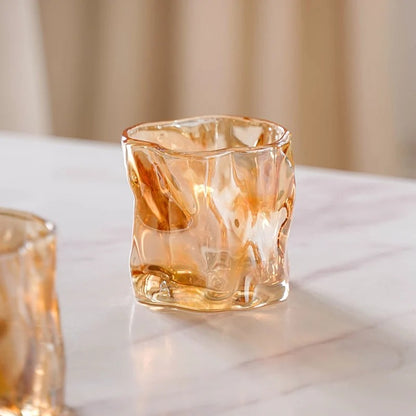 Two amber crinkle glass candle jars on marble surface, close-up texture detail