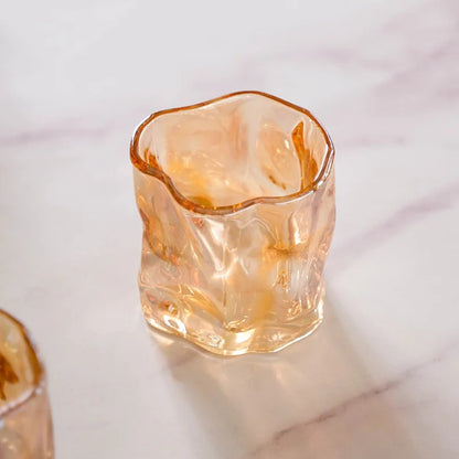 Two amber crinkle glass candle jars side by side on marble dining table