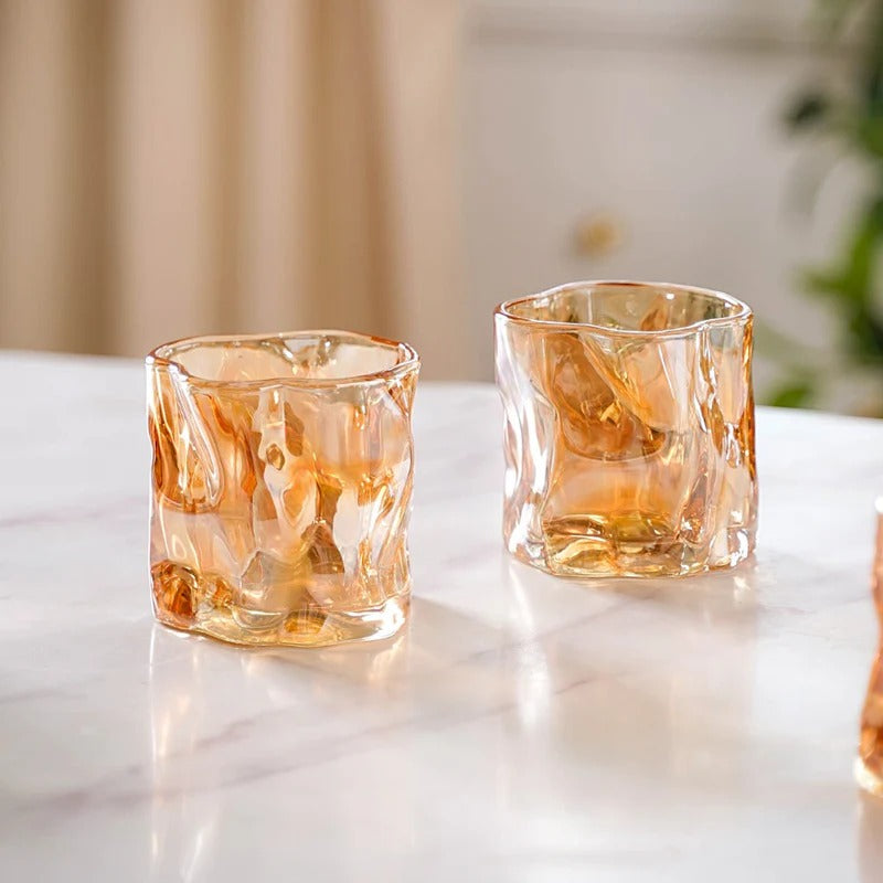 Set of 6 amber crinkle glass candle jars arranged on white display stand, hand picking one up