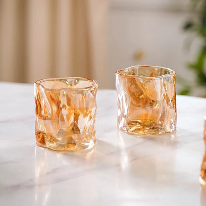 Set of 6 amber crinkle glass candle jars arranged on white display stand, hand picking one up