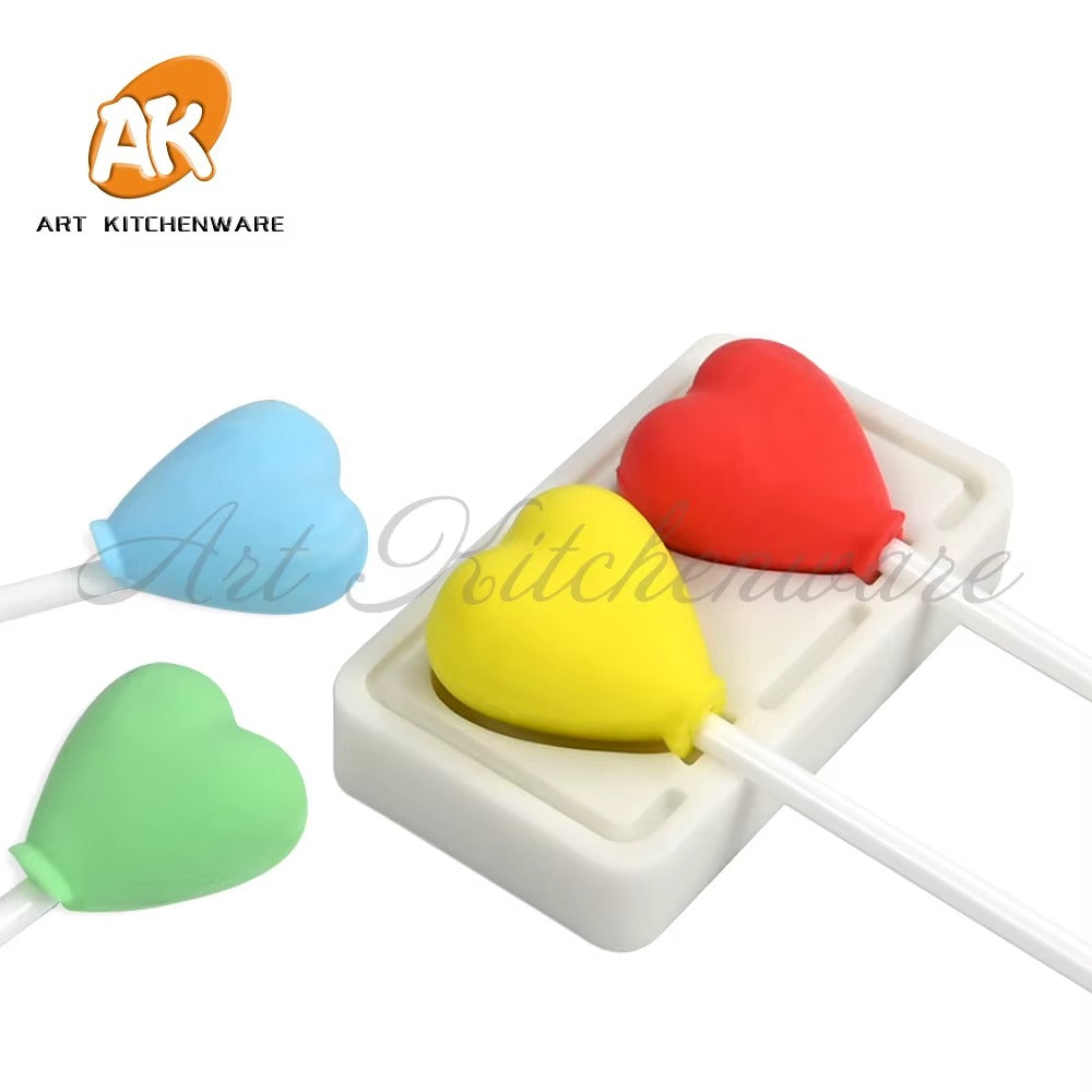 Coloured heart-shaped sample castings on sticks beside a two-cavity mould; samples and sticks not included
