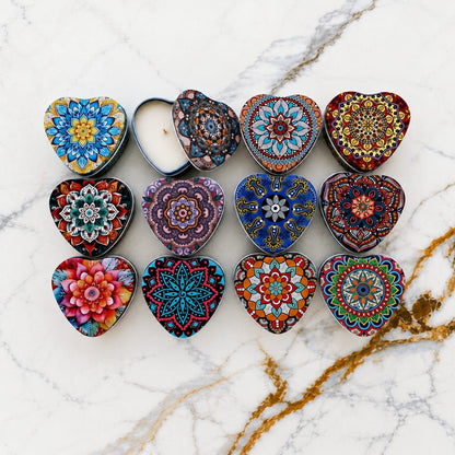 12 heart-shaped mandala candle tins with vibrant boho decorative lids displayed on marble surface, one tin open showing candle and wick