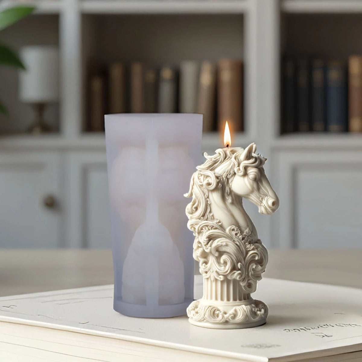 Ornate horse-head candle mould beside a finished sample candle with scrollwork and a pedestal base