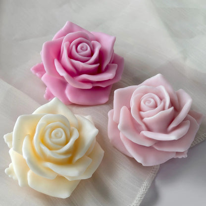 3D rose silicone candle mould – four finished candles in pink and white on white surface with green leaf accent