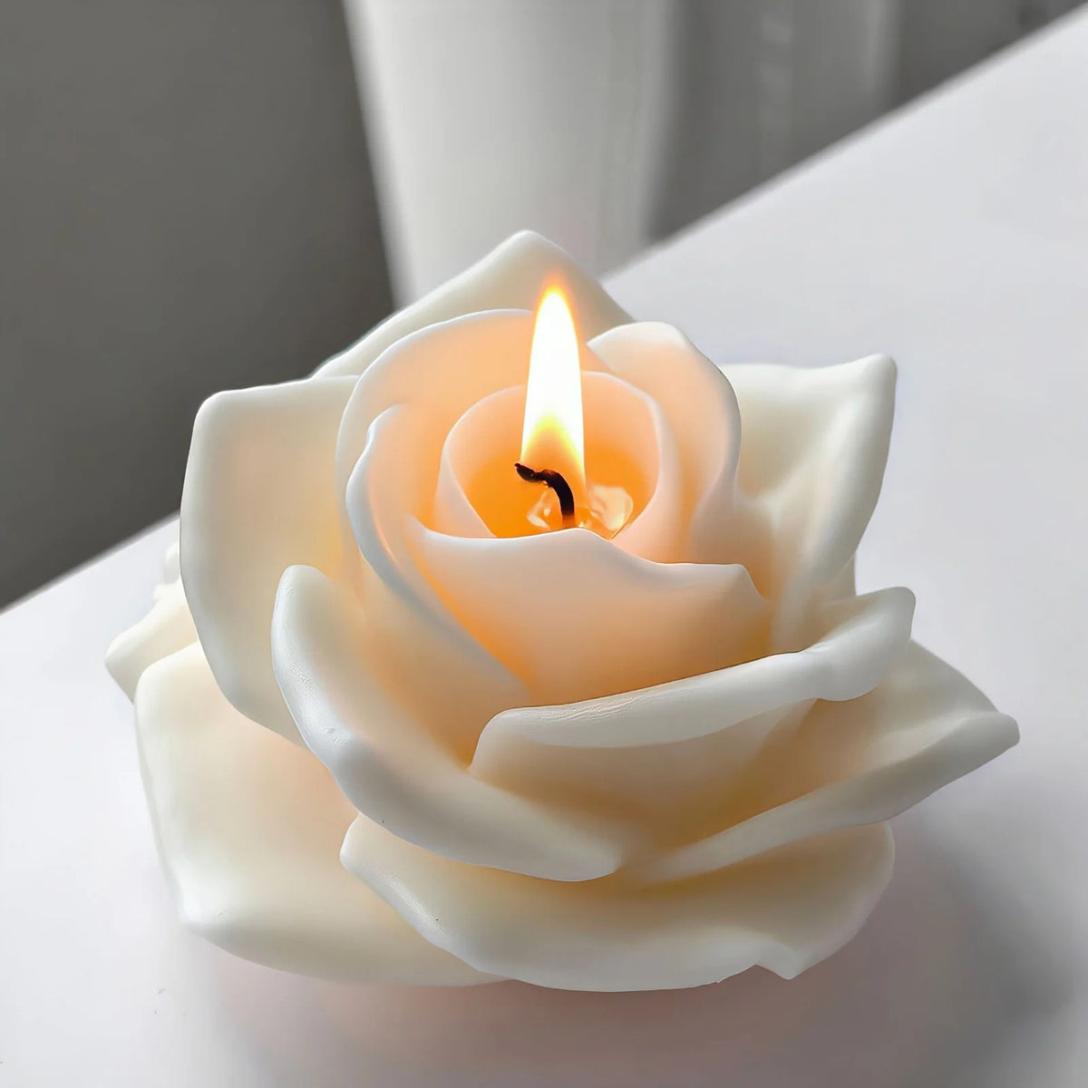 3D rose silicone candle mould – lit white ivory rose candle glowing with warm amber flame