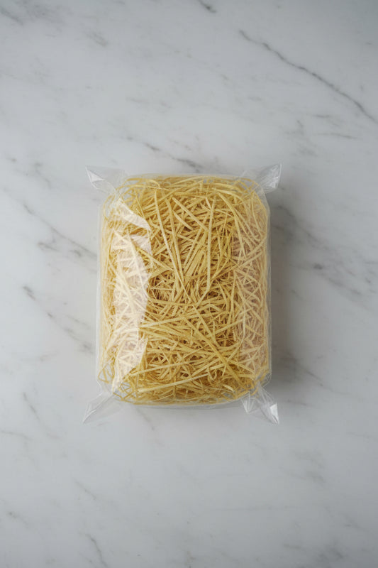 Yellow straw shredded wooden gift box filler in a clear bag