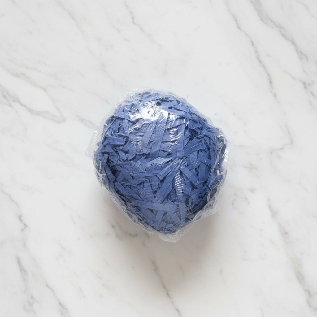 Navy blue shredded paper gift box filler in a clear bag