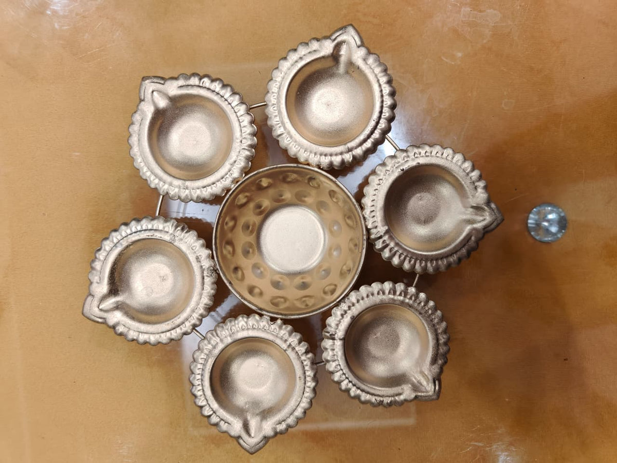 Gold 6-diya urli set with 6 scalloped diya holders surrounding central bowl, top view