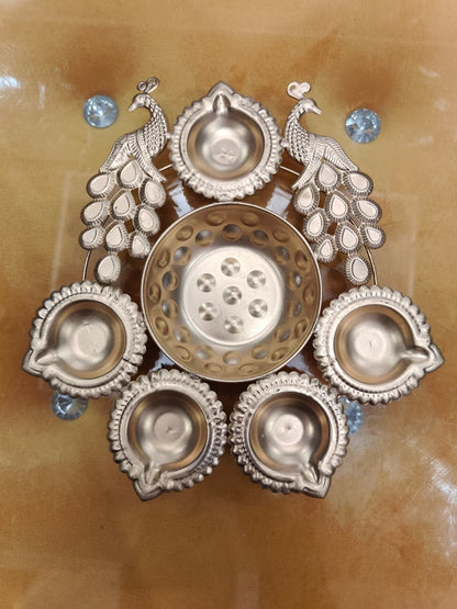 Gold twin peacock diya urli with 2 standing peacock figures and 5 scalloped diya holders surrounding central bowl, top view