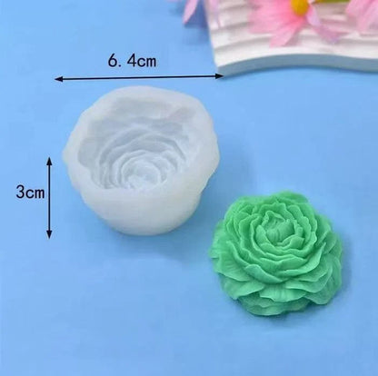 White peony silicone mould 6.4cm x 3cm with green finished peony candle cast beside it on blue background