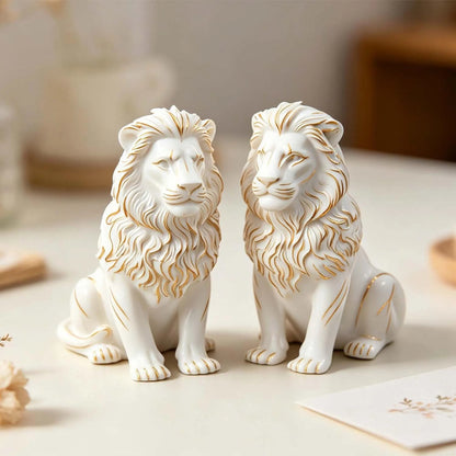 Two seated lion sample castings with gold-coloured detailing on their manes