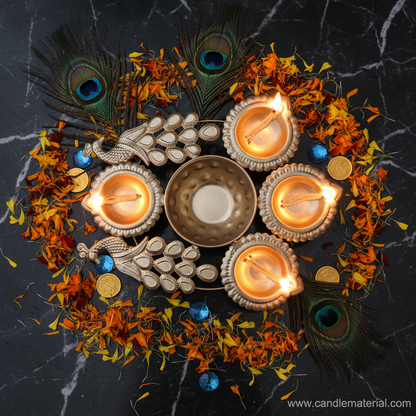 Overhead flat lay of gold compact twin peacock diya urli with lit diyas on dark marble with peacock feathers and gems