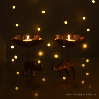 Elephant tall stem lotus diya holders with lit candles, fairy light bokeh