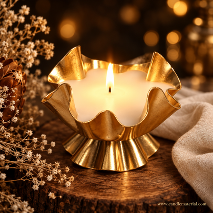 Gold ruffled lotus petal candle vessel with lit white candle, dark moody background with golden bokeh