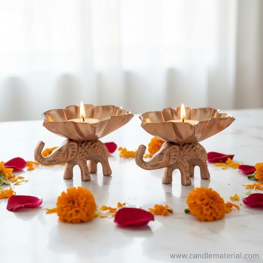 Elephant lotus diya holders with lit candles on marble surface with marigolds