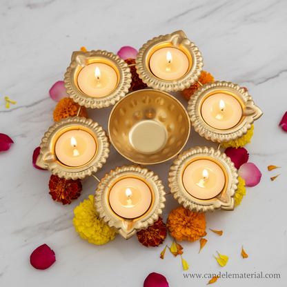 Gold 6-diya urli with lit tealight candles on marble surface with marigold flowers