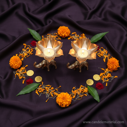 Flat lay of elephant tall stem lotus diya holders with puja styling and gold coins