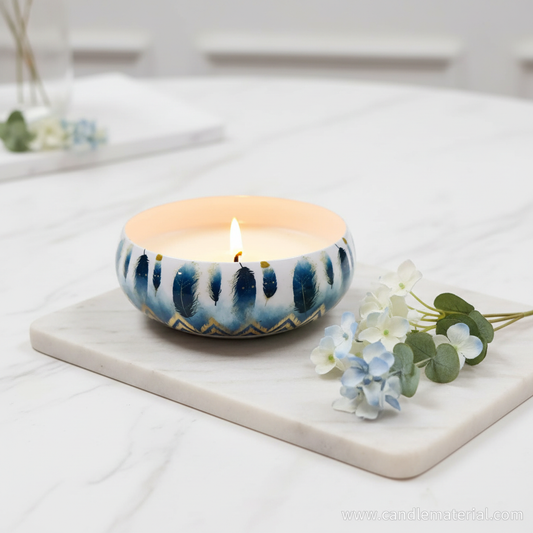 Blue feather candle bowl with lit candle on marble surface with blue flowers