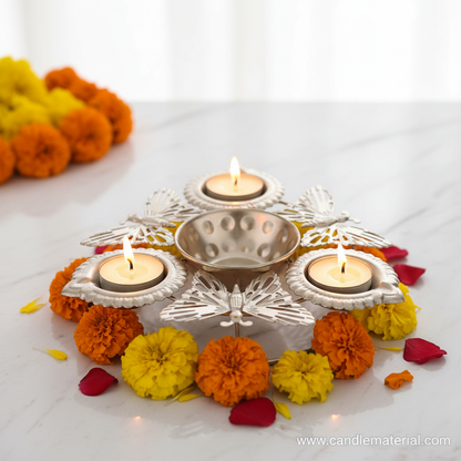 Silver butterfly diya set with lit tealight candles on marble surface with marigold flowers