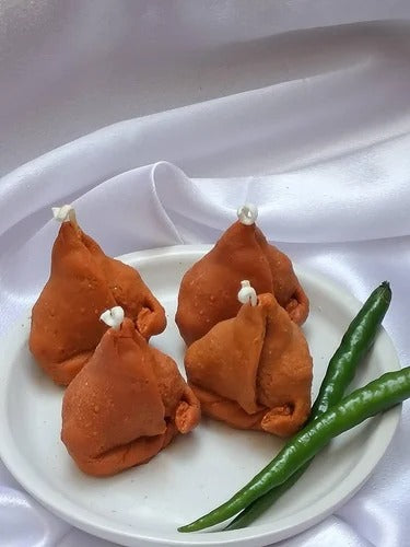 White silicone samosa mould next to a finished golden samosa candle