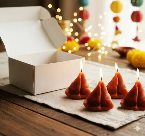 Close-up of a terracotta-coloured samosa candle with wick on a dark surface with salt