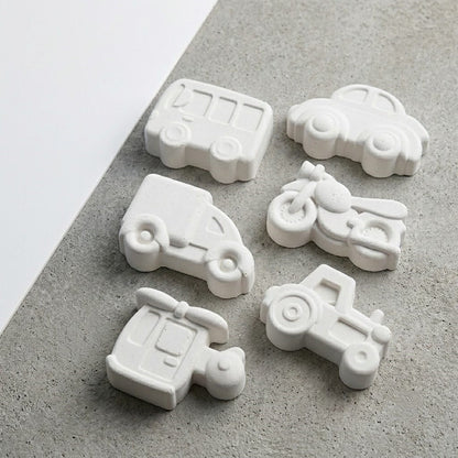 White wax melts cast from vintage vehicles mould showing bus, car, van, motorcycle, scooter and tractor shapes
