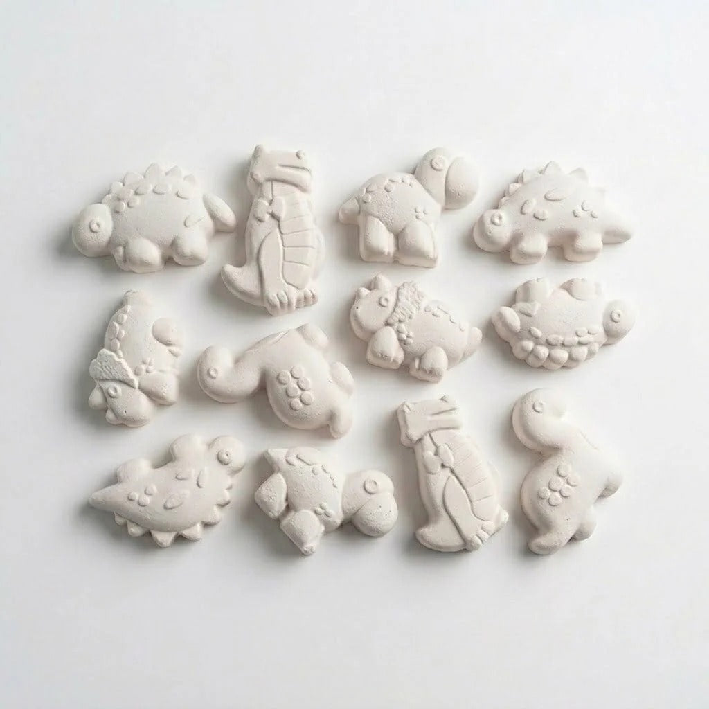 White clay pieces cast from dinosaur mould showing 12 different chubby dino species