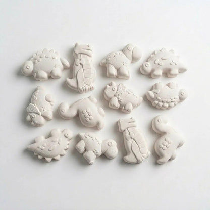 White clay pieces cast from dinosaur mould showing 12 different chubby dino species